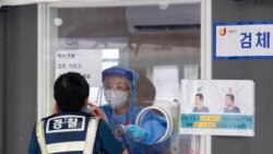 A medical worker in a booth takes a nasal sample from a police officer during coronavirus testing at a makeshift testing site in Seoul, South Korea, Sept. 25, 2021.