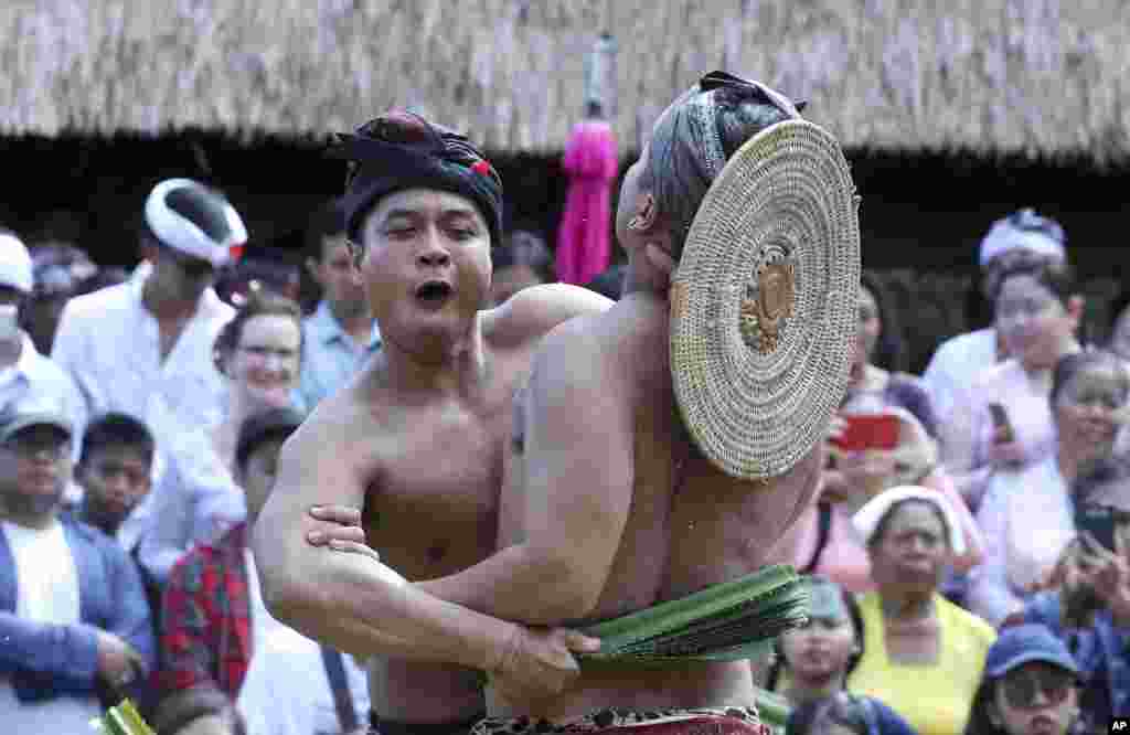 Balinese men fight with sticks wrapped in thorny pandanus leaves during a village festival ceremony in Bali, Indonesia.