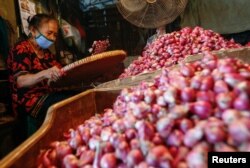 Seorang pekerja mengenakan masker wajah memilah bawang di pasar tradisional di tengah pandemi virus corona (Covid-19) di Jakarta, 3 Agustus 2020. (Foto: Reuters)