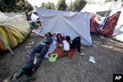 A Venezuelan refugee family rests outside a makeshift camp before going out to find any kind of work in Quito, Ecuador, Aug. 9, 2018.