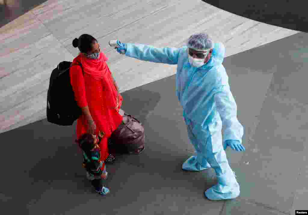 A health worker in personal protective equipment (PPE) checks the temperature of a passenger at a railway station, amid the spread of the coronavirus disease (COVID-19), in Mumbai, India November 27, 2020. REUTERS/Francis Mascarenhas TPX IMAGES OF THE