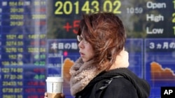 Seorang wanita berjalan melewati sebuah perusahaan sekuritas di Tokyo, Senin, 7 Januari 2019. (Foto: AP)