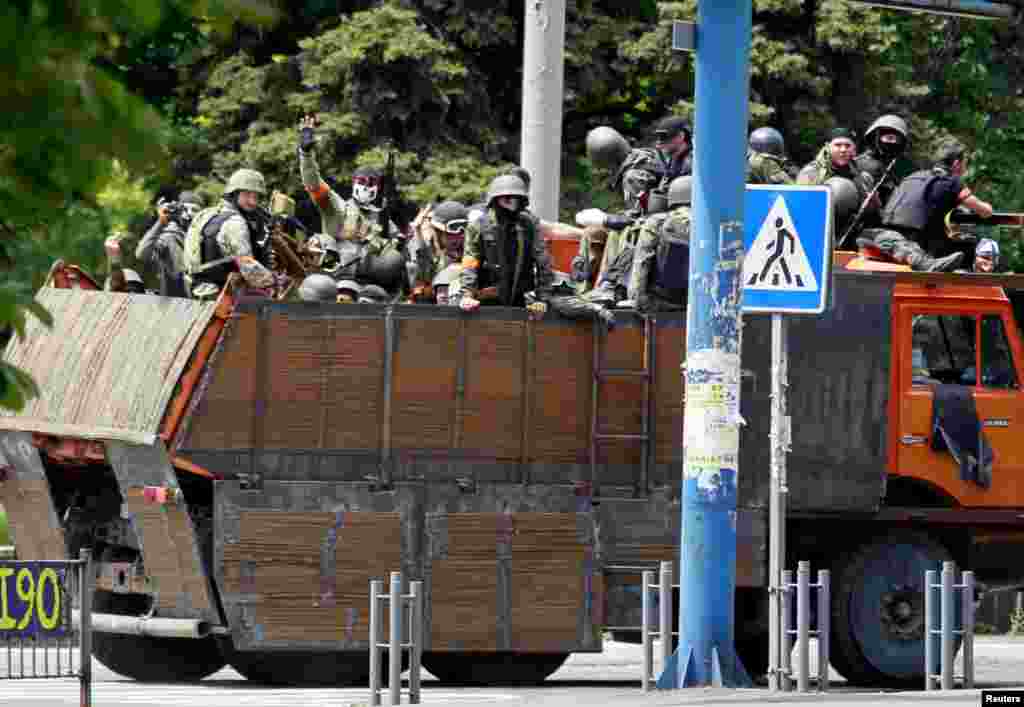Ukrainian troops riding on the back of a truck gesture to local residents gathered near the site of fighting, Mariupol, June 13, 2014.&nbsp;