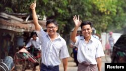 Reuters reporters Wa Lone and Kyaw Soe Oo gesture as they walk to Insein prison gate after being freed, after receiving a presidential pardon in Yangon, Myanmar, May 7, 2019. 