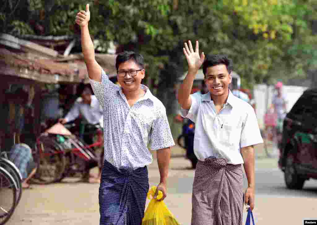 Reuters reporters Wa Lone and Kyaw Soe Oo gesture as they walk to Insein prison gate after being freed, after receiving a presidential pardon in Yangon, Myanmar, May 7, 2019. 