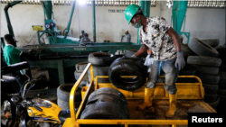 A worker offloads used car tires from a cargo tricycle in preparation for recycling at the Freetown waste management recycle factory in Ibadan, Nigeria September 17, 2021. (REUTERS/Temilade Adelaja)