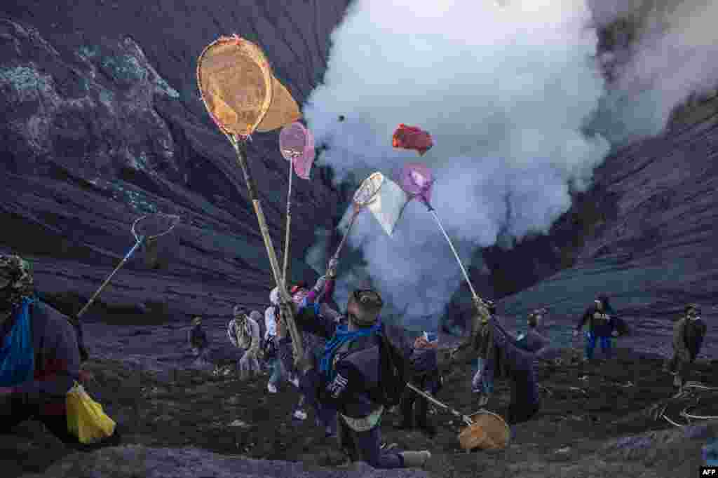 People try to catch offerings thrown by Tengger tribe people off the summit of the active Mount Bromo volcano in Probolinggo, East Java province, June 26, 2021, during the Yadnya Kasada festival to seek blessings from the main deity.