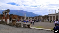 FILE - Tourists stroll past the remains of Pompeii's forum.