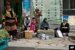 FILE - In this photo taken July 17, 2014, Uighur residents gather at a road side stall in the city of Aksu in western China's Xinjiang province.