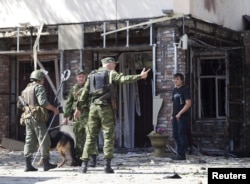 FILE - A serviceman directs a pedestrian away from the scene of a suicide bomb attack in Grozny, the capital of Russia's Chechnya region, Aug. 31, 2011.