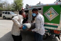 People carry a medical oxygen cylinder at a charging station on the outskirts of Prayagraj, India, Friday, April 23, 2021. I