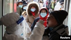 中国河北省石家庄一名身穿防护服的医护人员在给居民做病毒核酸检测。（2021年1月6日）