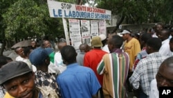 Quelques passants lisent les titres des journaux étalés sur une place publique à Kinshasa, RDC, 29 juillet 2006.