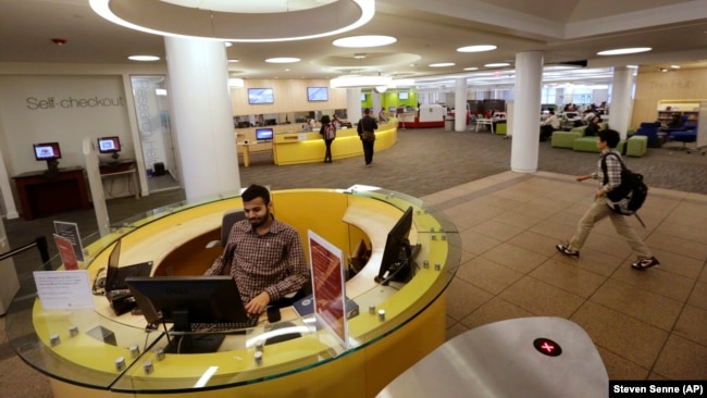 Libraries offer more than just books. Northeastern University graduate student Shabbir Hussain, of Indore, India, left, views a computer screen at the entrance to the Snell Library on the Northeastern University campus in Boston on Tuesday, May 24, 2016. (AP Photo/Steven Senne)