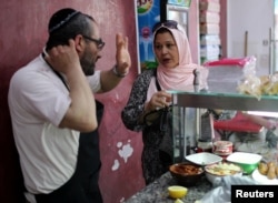 A Tunisian Muslim woman buys food from a Jewish restaurant in Djerba, Tunisia, May 1, 2018.