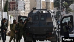 一名以色列士兵在约旦河西岸发生的冲突中向巴勒斯坦抗议者发射催泪弹