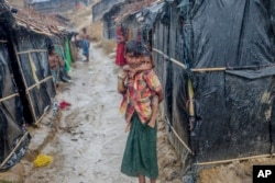 A Rohingya Muslim boy, who crossed over from Myanmar into Bangladesh, holds his brother outside his shelter as it rains in Balukhali refugee camp, Bangladesh, Thursday, Sept. 28, 2017.