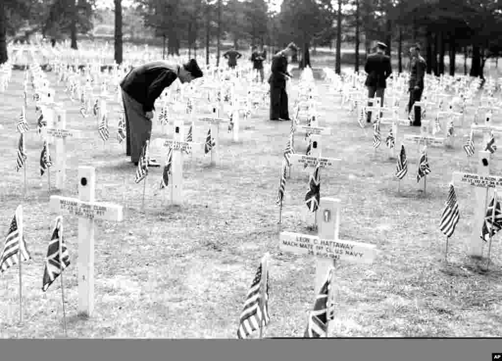 1945年5月30日美国军人在伦敦以南的萨里布鲁克伍德公墓纪念日仪式之后，寻找朋友的坟墓。
