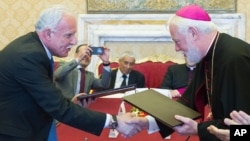 Vatican Foreign Minister Paul Gallagher, right, and his Palestinian counterpart, Riad al-Malki, shake hands after signing a treaty — covering church operations in parts of the Holy Land under Palestinian control — at the Vatican, June 26, 2015.