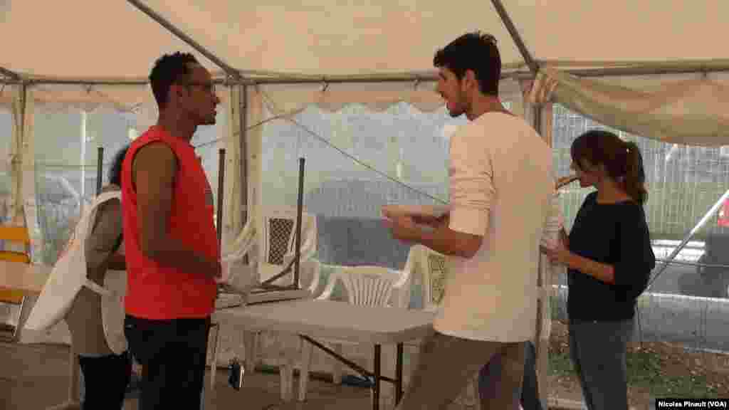 Un Erythréen discute avec des volontaires dans le centre d&#39;accueil de la Croix Rouge italienne derrière la gare de Tiburtina, Rome, 5 octobre 2015 (Nicolas Pinault/VOA). &nbsp;