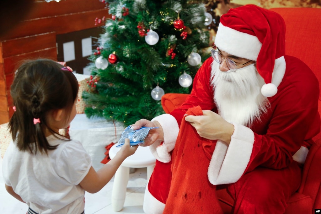 A man dressed as Santa Claus gives a present to a child at a shopping mall in Petaling Jaya, Malaysia, Dec. 25, 2017.