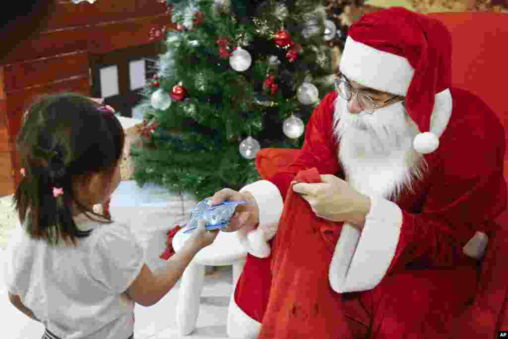 A man dressed as Santa Claus gives a present to a child at a shopping mall in Petaling Jaya, Malaysia, Dec. 25, 2017.
