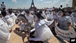 Demonstrators dressed as mime artists hold placards that read "no to the euthanasia of elderly people, solidarity is urgent," at Trocadero plaza in Paris, France, June 24, 2014. 