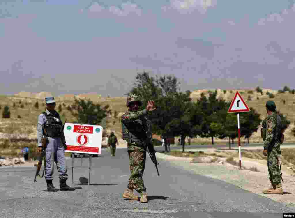 An Afghan National Army (ANA) soldier gestures at vehicles to stop at a check point near the British-run military training academy Camp Qargha, in Kabul, Aug. 6, 2014.