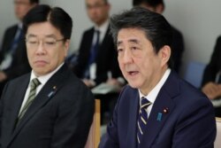Perdana Menteri Jepang Shinzo Abe (kanan) dan Menteri Kesehatan Katsunobu Kato (kiri) menghadiri pertemuan di kantor pusat pengendalian penyakit menular COVID-19 yang baru di kantor perdana menteri di Tokyo pada 26 Februari 2020. (Foto: AFP)