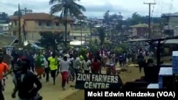 FILE - Hundreds of youths run through the streets of Ekona, cheering, waving palm fronds, and holding signs demanding independence in this image taken from video, Sept. 22, 2017. 