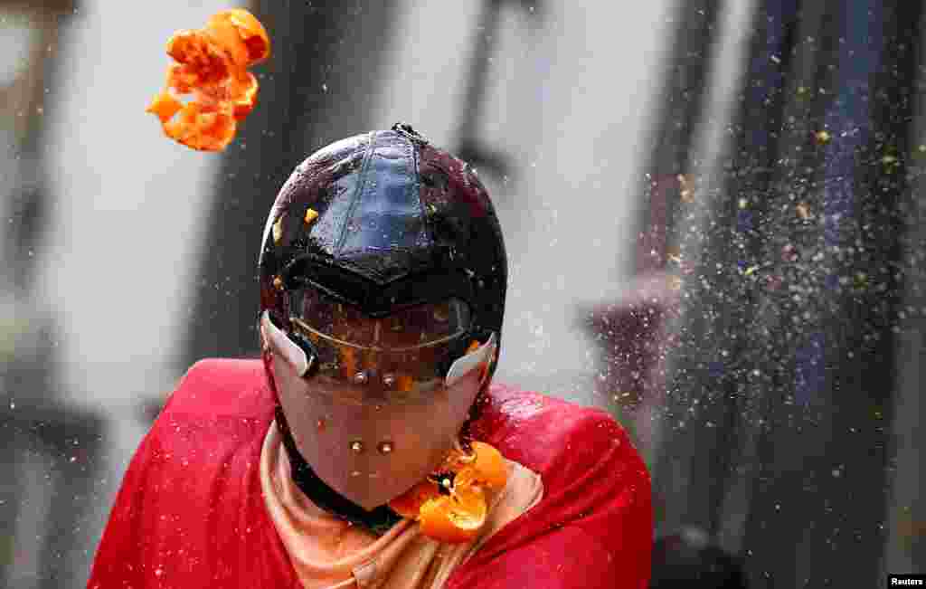 A member of a team is hit by oranges during an annual carnival battle in the northern Italian town of Ivrea, Italy.