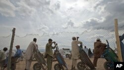 Men line up with their wheelbarrows to transport supplies for families displaced by military operations last year against militants in Bara, at the United Nations High Commission for Refugees-supported Jalozai camp in Pakistan's northwest, April 11, 2012.