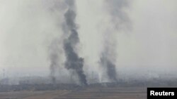 De la fumée s'échappe à Bartila, à l'est de Mossoul lors des combats contre le groupe État islamique, Irak, le 18 octobre 2016. 