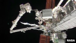 Astronaut Rick Mastracchio holds the degraded pump module while the International Space Station's robotic arm guides the module to a grapple fixture. (Credit: NASA TV)