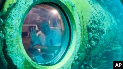 Fabien Cousteau waves from inside Aquarius Reef Base, a laboratory 63 feet below the surface in the waters off Key Largo, in the Florida Keys National Marine Sanctuary, June 24, 2014.