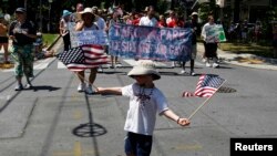 Un niño con la bandera estadounidense en la mano participa de un desfile.