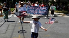 Un niño con la bandera estadounidense en la mano participa de un desfile.