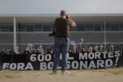 Demonstran memegang spanduk dan salib untuk memberi penghormatan kepada 600.000 korban COVID-19 di Brazil. Mereka juga menentang penanganan pandemi penyakit virus corona oleh Presiden Jair Bolsonaro, di Brasilia, Brazil, 8 Oktober 2021. (Foto: Reuters)