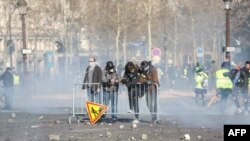 Los manifestantes están detrás de una cerca durante los enfrentamientos con las fuerzas de la policía antidisturbios en los Campos Elíseos en París