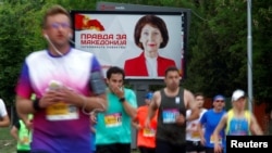 Athletes run during the Skopje Marathon next to an election campaign poster of for VMRO-DPMNE presidential candidate Gordana Siljanovska-Davkova, in Skopje, North Macedonia, May 4, 2019.