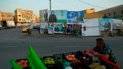 FILE - A street vendor who sells fruits passes by campaign posters for upcoming parliamentary elections in Baghdad, Iraq, Oct. 7, 2021.