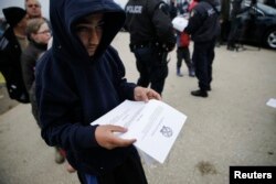 A boy reads an announcement distributed by Greek police officers informing refugees and migrants that the borders to Macedonia are closed and they should consider moving to relocation centers, at a makeshift camp at the Greek-Macedonian border near the village of Idomeni, Greece, March 18, 2016.