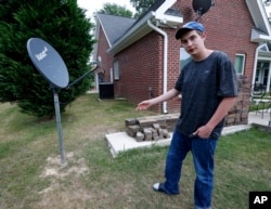 In this May 8, 2019, photo, Riley Shaw talks about his family's internet at his home outside Starkville, Miss. The satellite dish allows a certain amount of high-speed data each month and then slows to a crawl. (AP Photo/Rogelio V. Solis)