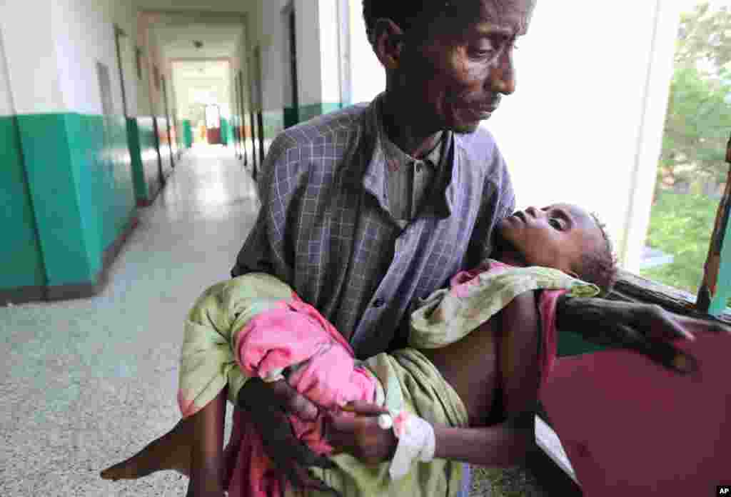 An man carries his malnourished child through the corridors inside Banadir hospital in Somalia's capital, Mogadishu, Aug. 9, 2011. (Reuters)