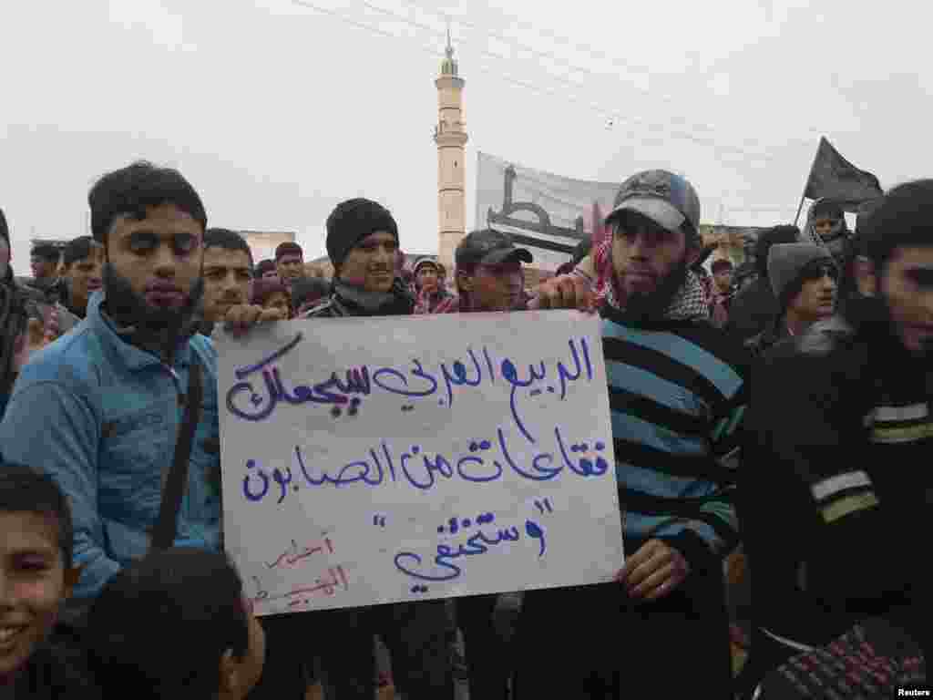 Demonstrators hold a sign that reads "The Arab spring will turn you (Syrian President Bashar al-Assad) into soap bubbles that will disappear" during a protest in Habeet near Idlib, Syria, January 6, 2013. 
