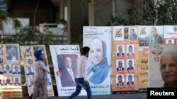 Des résidents marchent devant les affiches électorales dans le cadre des élections parlementaires à Amman, Jordanie, le 16 septembre 2016.