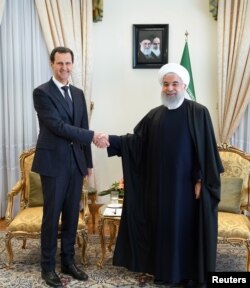 A Syria's President Bashar al-Assad shakes hands with Iranian President Hassan Rouhani in Tehran, in this handout released by SANA, Feb. 25, 2019.