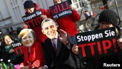 Protesters wear masks of U.S. President Barack Obama and German Chancellor Angela Merkel as they demonstrate against the Transatlantic Trade and Investment Partnership (T-TIP) free trade pact at the Hannover Messe in Hannover, Germany, April 24, 2016. 