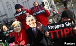 Protesters wear masks of U.S. President Barack Obama and German Chancellor Angela Merkel as they demonstrate against the Transatlantic Trade and Investment Partnership (T-TIP) free trade pact at the Hannover Messe in Hannover, Germany, April 24, 2016.
