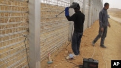 African migrants work at the site where Israel builds a barrier along the border with Egypt in southern Israel, February 15, 2012.